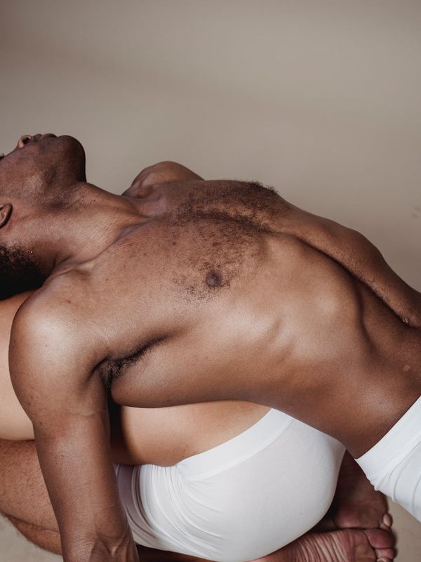 Man in a dynamic stretching pose in a minimalist studio.