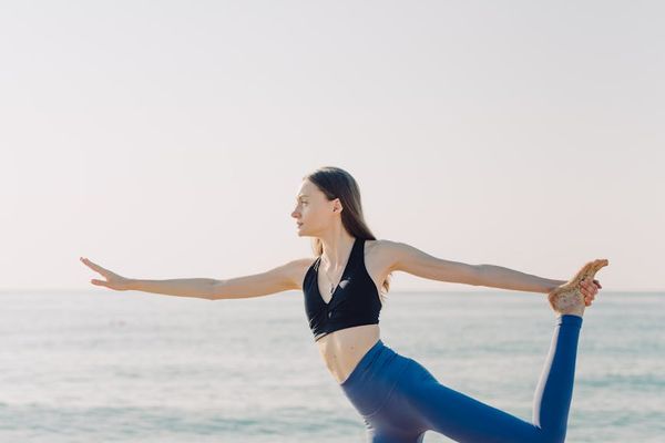 Person balancing on one leg with a serene background.